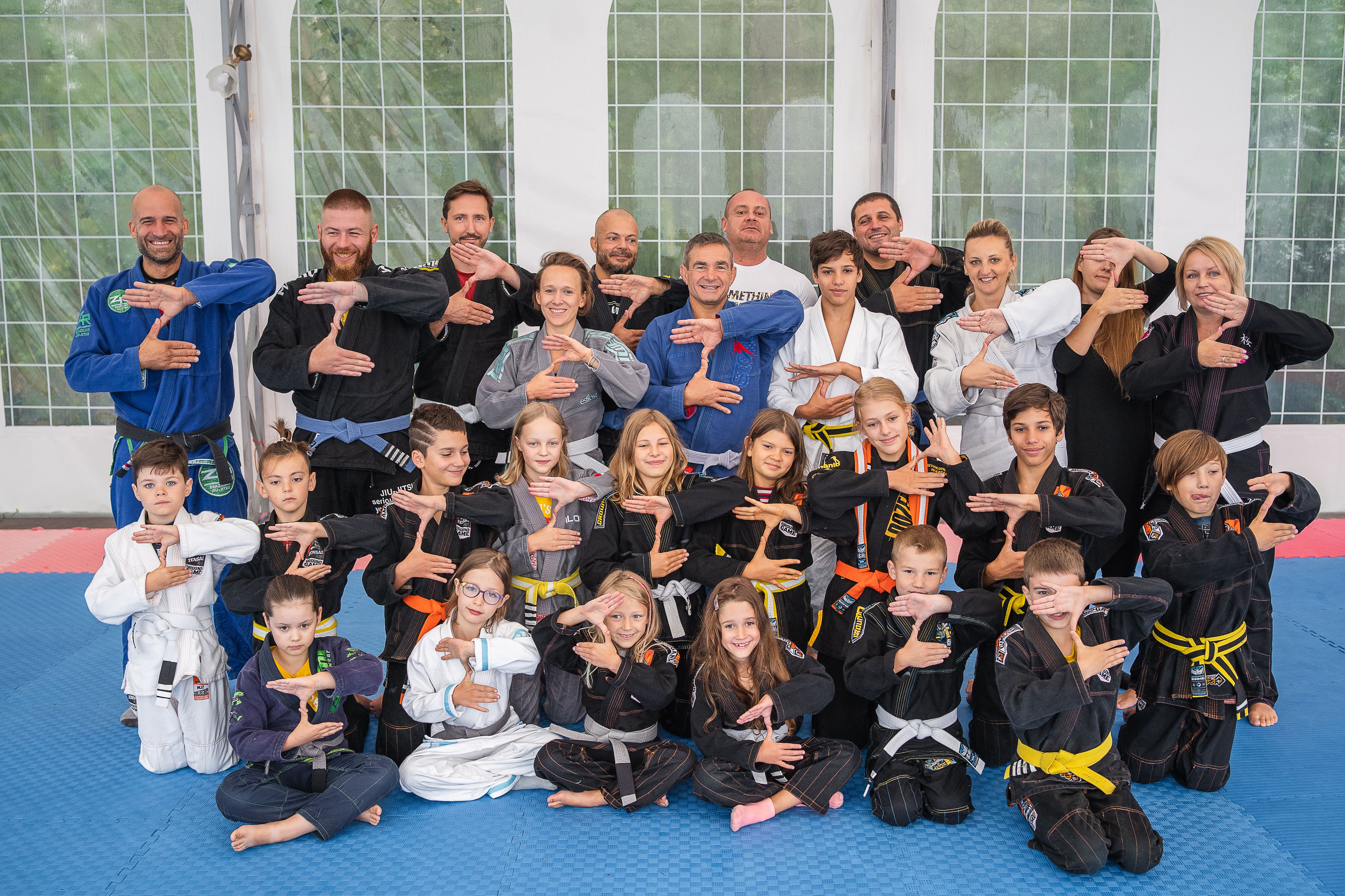 BJJ team seating at the platform holding medals and trophies